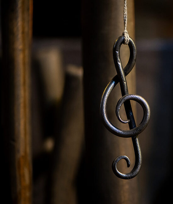 a metal sheet music key hangs in a rope in a blacksmith's workshop